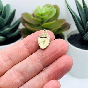 Puede incluir: Encanto de fresa de metal dorado con superficie texturizada. El encanto tiene un bucle en la parte superior para sujetarlo a joyas u otras manualidades.