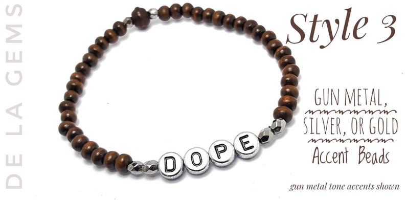 以下が含まれることがあります： 「DOPE」とスペルされたシルバーのアクセントビーズが付いたブラウンの木製ビーズブレスレット。ブレスレットは白い背景に映し出されています。ガンメタル、シルバー、またはゴールドのアクセントビーズをご用意しています。