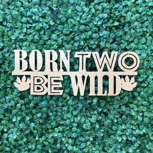 May include: Wooden sign with the text "Born to Be Wild" in gold lettering. The sign has a rustic look and is perfect for a baby shower or birthday party.