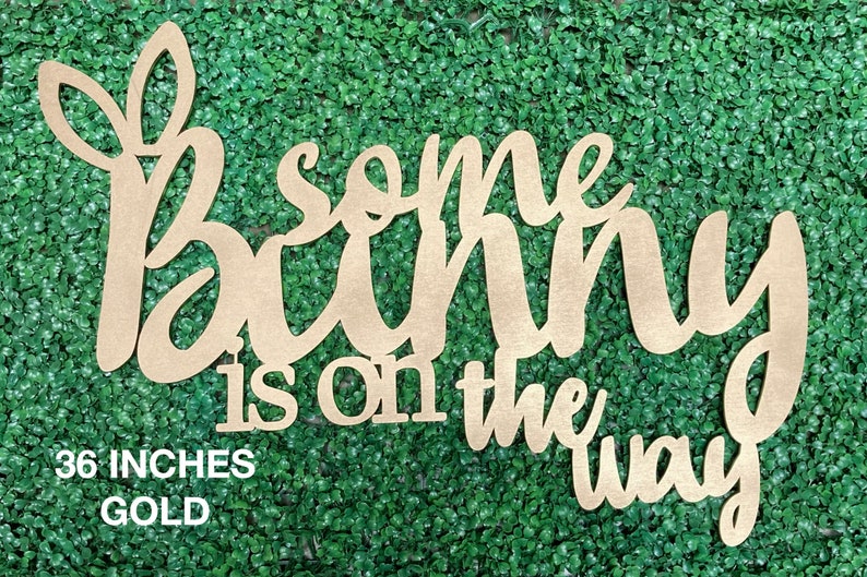May include: Gold wooden sign with the text "Some bunny is on the way" in a cursive font. The sign is 36 inches long.