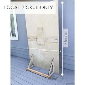 May include: A large, unfinished wooden board, 7 feet tall and 4 feet wide, with attached wooden supports. The text "LOCAL PICKUP ONLY" is displayed at the top. The board has several hinged wooden pieces attached to its surface.
