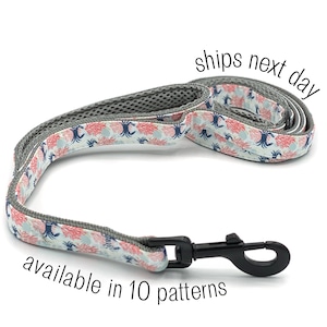 May include: A gray and white dog leash with a black metal clip. The leash has a pattern of pink and blue crabs on a white background. The leash is made of a durable, water-resistant material.