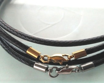 May include: Close-up of three black leather necklaces with gold and silver clasps. The necklaces are braided and have a shiny finish. The clasps are lobster claw style.