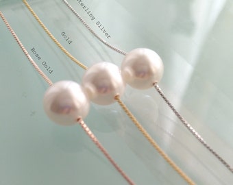 May include: Three necklaces with large, round, white pearls. The chains are in rose gold, gold, and sterling silver. The text in the image reads "Rose Gold", "Gold", and "Sterling Silver". The background is a light blue color.