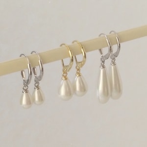 Könnte beinhalten: Drei Paar Ohrringe mit perlmuttartigen, tropfenförmigen Anhängern. Die Ohrringe sind in Gold-, Silber- und Rhodium-Finish erhältlich.