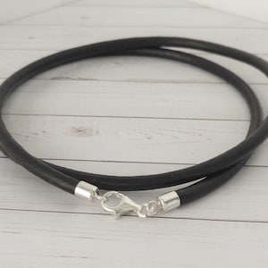 May include: A black leather cord necklace with a silver clasp and lobster claw closure.
