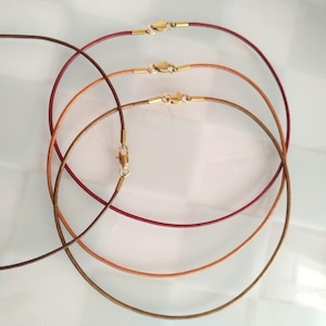 May include: Three leather cord necklaces in brown, orange, and red with gold clasps.
