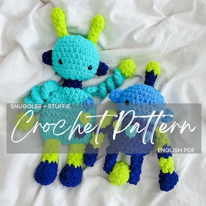 Könnte beinhalten: Zwei gehäkelte Roboter-Plüschtiere, eines blau und eines türkis, mit grünen und blauen Akzenten. Die Plüschtiere liegen auf einer weißen Oberfläche. Der Text "Crochet Pattern" ist über das Bild gelegt.  ENGLISH PDF