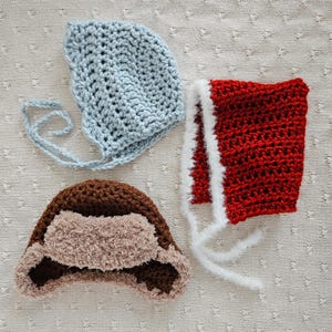 May include: Three crocheted hats in different colors and styles. A light blue hat with a long tie, a red hat with a white trim, and a brown hat with a fluffy brown brim.