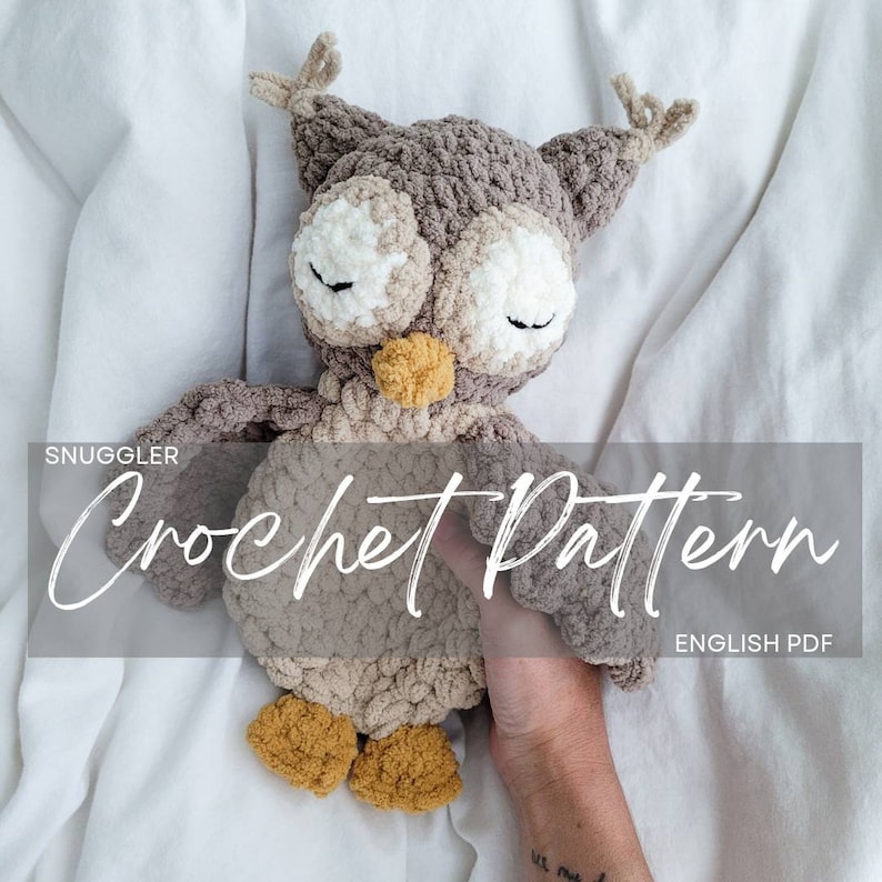 May include: A crocheted owl plush toy in brown, beige, and yellow. The owl is lying down with its eyes closed. The text "Snuggler Crochet Pattern English PDF" is visible in the image.