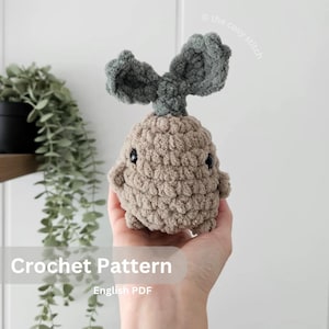 May include: Crochet pattern for a brown and green amigurumi sprout with a cute face. The pattern is available as an English PDF download. "Crochet Pattern" and "English PDF" are written on the image.
