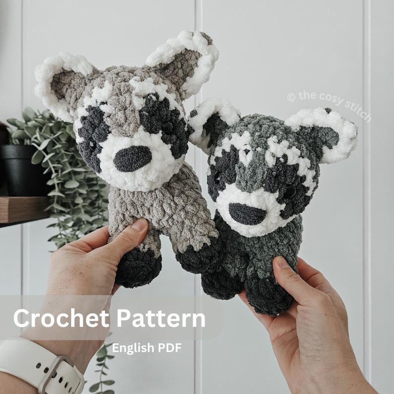 K&ouml;nnte beinhalten: H&auml;kelanleitung f&uuml;r zwei graue und wei&szlig;e Waschb&auml;r-Amigurumi-Pl&uuml;schtiere. Das Muster ist als englischer PDF-Download erh&auml;ltlich. Der Text "Crochet Pattern" und "English PDF" ist im Bild sichtbar.