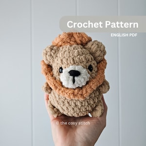 May include: Crochet pattern for a brown and orange lion amigurumi toy. The lion has a fluffy mane and a cute face with black eyes and a black nose. The pattern is available in English PDF format.