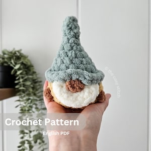 Puede incluir: Patrón de crochet para un gnomo con un gorro verde, barba marrón y cara blanca. El patrón está disponible en formato PDF en inglés.