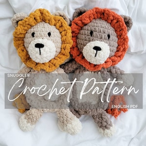 May include: Two crocheted lion plushies, one with a brown mane and the other with an orange mane. The plushies are sitting on a white surface. The text "Snuggler Crochet Pattern ENGLISH PDF" is visible in the image.