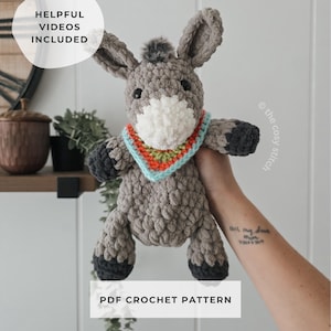 May include: A handmade gray crochet donkey plushie with a white muzzle and a colorful scarf. The donkey has dark gray hooves and ears. The text "PDF Crochet Pattern" is displayed below the donkey.