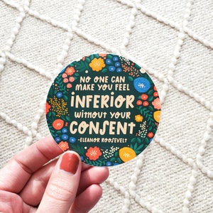 May include: A round sticker with a green background and colorful floral designs. The sticker features the quote "No one can make you feel inferior without your consent" attributed to Eleanor Roosevelt.
