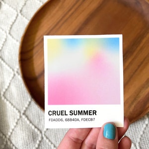 Square sticker with a gradient of pink, blue, and yellow above the words Cruel Summer and the hex codes FDADD6, 68B4DA, and FDECB7