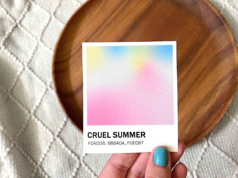 Square sticker with a gradient of pink, blue, and yellow above the words Cruel Summer and the hex codes FDADD6, 68B4DA, and FDECB7