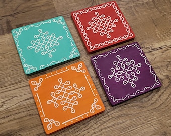 May include: Four square coasters with a white geometric design on a wood background. The coasters are painted in teal, red, purple, and orange.