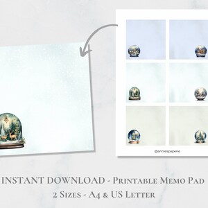 Może przedstawiać: Drukowany bloczek z notatnikiem z zimową sceną w środku kuli śnieżnej. Kula śnieżna przedstawia zasneżony las z małą chatką i dwoma jeleniami. Bloczek z notatnikiem jest dostępny w dwóch rozmiarach: A4 i US Letter.