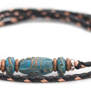 May include: A black and copper braided leather cord necklace with a turquoise blue and copper bead.