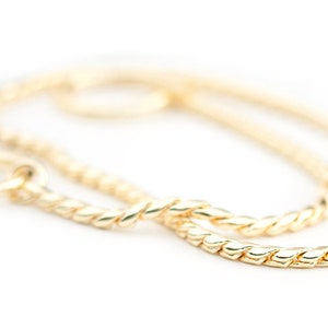 May include: A gold chain necklace with a twisted rope design. The chain is made of a thick, durable metal and has a polished finish.