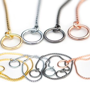 May include: Four twisted chain dog collars in gold, silver, black, and rose gold. Each collar has a round ring at the end.