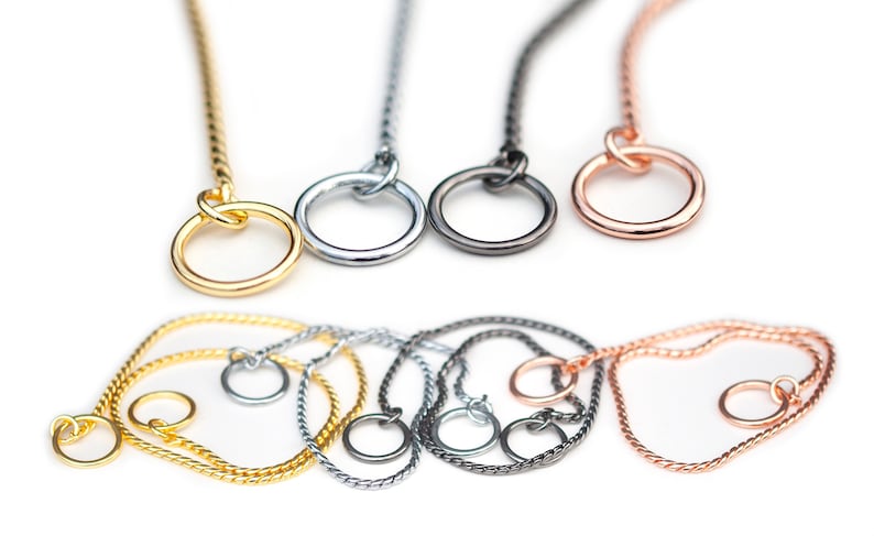 May include: Four twisted chain dog collars in gold, silver, black, and rose gold. Each collar has a round ring at the end.