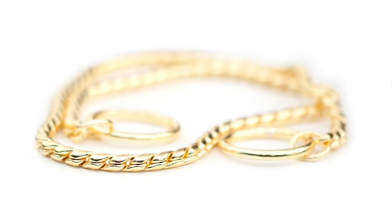May include: A gold chain necklace with a twisted rope design and two circular clasps.