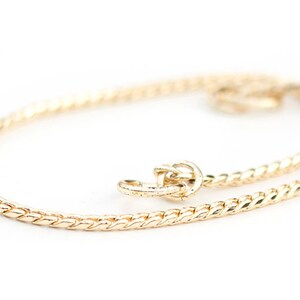 May include: A gold chain necklace with a twisted design. The chain is delicate and has a clasp closure.