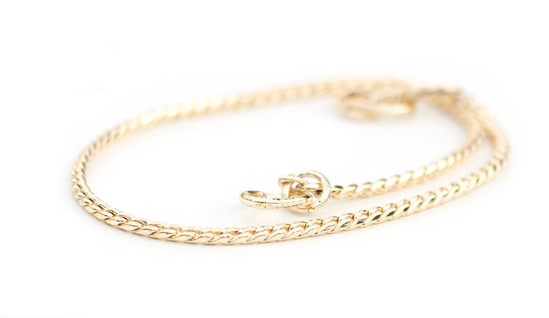 May include: A gold chain necklace with a twisted design. The chain is delicate and has a clasp closure.