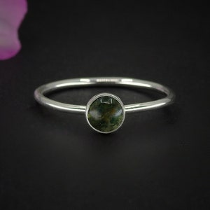 May include: A silver ring featuring a green moss agate gemstone.