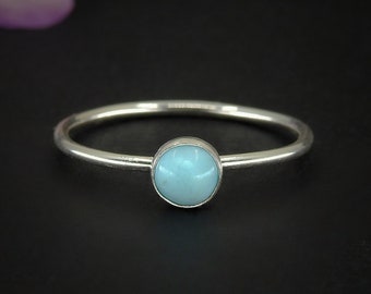 May include: A silver ring with a light blue gemstone set in the center.