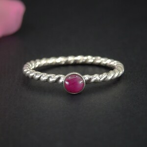 May include: A silver ring with a twisted band and a pink gemstone in the center.