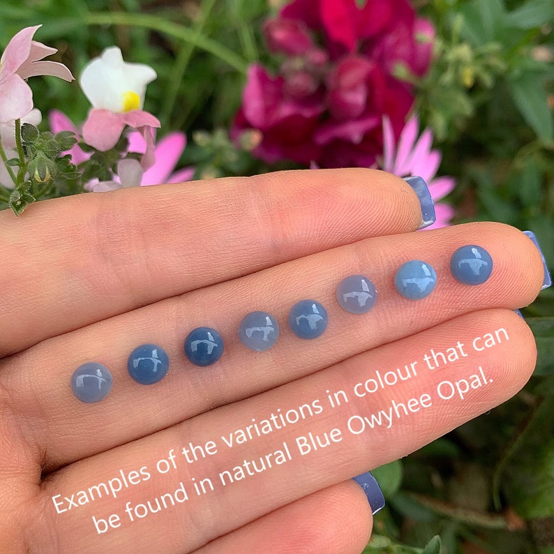 May include: A close-up of seven blue Owyhee opal cabochons, showing the variations in color found in this type of opal. The cabochons are arranged in a row, from lightest to darkest blue.