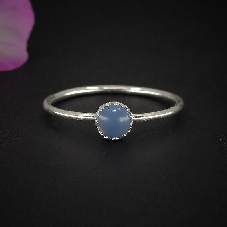 May include: A silver ring with a blue gemstone set in a scalloped bezel.