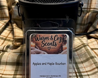 May include: A clear plastic clamshell container holding wax melts with a label reading Warm & Cozy Scents, Apples and Maple Bourbon, Handpoured in Somerset, PA, Soy Wax, (740) 516-1819, Facebook: Warm & Cozy Scents, and a URL link.