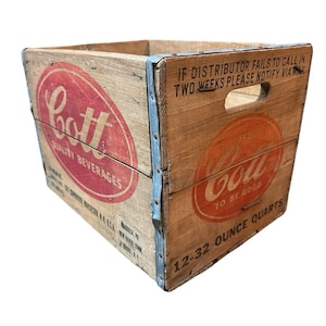 May include: Vintage wooden Cott soda crate with red and white oval logos. The crate has metal corner reinforcements and text that reads "Quality Beverages" and "To Be Good". It holds 12-32 ounce quarts.