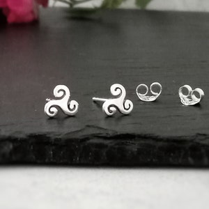 May include: A pair of silver earrings featuring a Celtic knot design. The earrings are small and delicate, ideal for everyday wear.