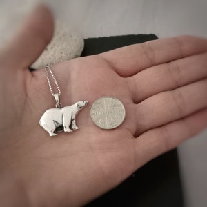 Puede incluir: Collar con colgante de oso polar plateado. El colgante es una escultura detallada de un oso polar. El collar est&aacute; junto a una moneda. El colgante mide aproximadamente 2,5 cm de largo.