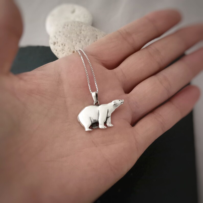Puede incluir: Collar con colgante plateado con dise&ntilde;o de oso polar. El colgante muestra un oso polar de pie con detalles. La cadena es fina y plateada, creando una joya elegante.