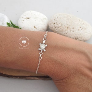 May include: A silver bracelet with a turtle pendant and a pearl. The bracelet is shown on an arm. The image includes the text "DESIGN FIORE DI LOTO, ETHNIC - VINTAGE - CHIC, Sterling Silver 925."