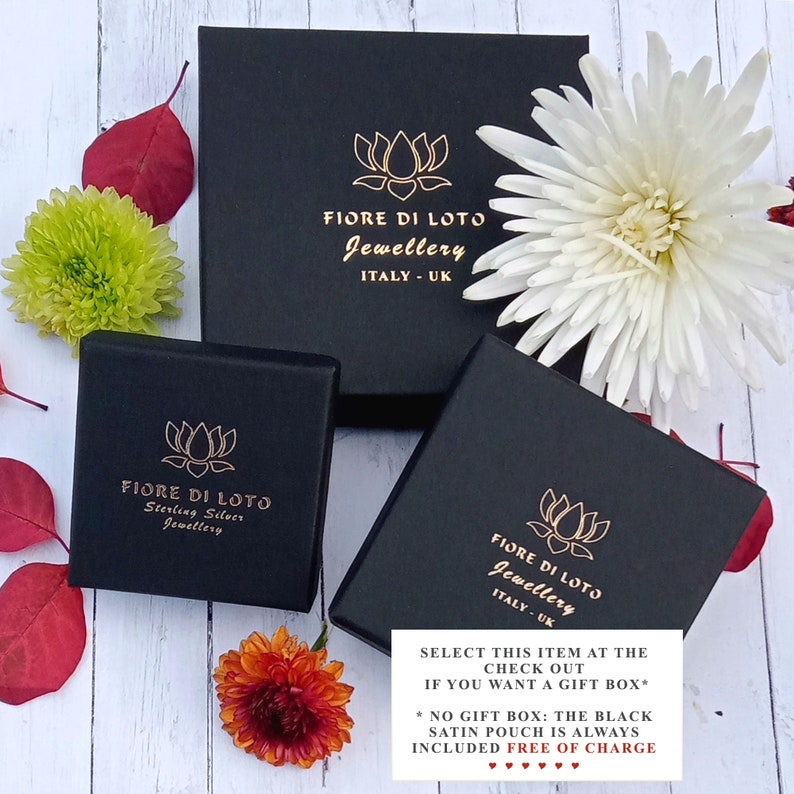 Puede incluir: Tres cajas de joyer&iacute;a negras con letras doradas y un logotipo de flor de loto. Las cajas est&aacute;n dispuestas con flores y hojas. El texto en las cajas dice "FIORE DI LOTO Jewellery ITALY - UK" y "Sterling Silver Jewellery". Una peque&ntilde;a tarjeta blanca dice "SELECT THIS ITEM AT THE CHECK OUT IF YOU WANT A GIFT BOX*"