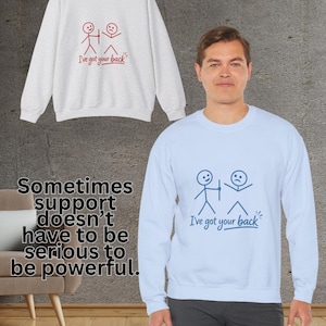 Può includere: Una felpa azzurra con una grafica a forma di omino stilizzato e la scritta "I've got your back". Una seconda felpa nell'immagine è grigio chiaro con la stessa grafica e testo. L'immagine include anche il testo "Sometimes support doesn't have to be serious to be powerful."