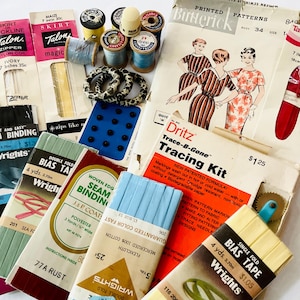 Könnte beinhalten: Eine Sammlung von Vintage-Nähzubehör, darunter Talon-Reißverschlüsse, Butterick-Schnittmuster, Schrägband, Nahtband, Garnrollen und ein Pauschen-Set. Die Artikel sind in verschiedenen Farben wie Rosa, Blau, Schwarz und Weiß auf einem hellen Hintergrund angeordnet.