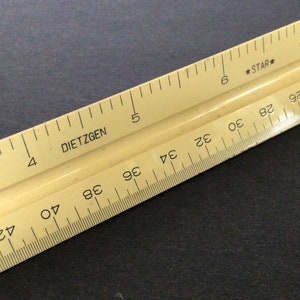 May include: A close-up of a yellow ruler with black markings. The ruler is labeled "DIETZGEN" and "STAR". The ruler is marked in inches and centimeters.