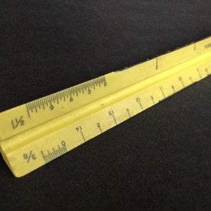 Könnte beinhalten: Ein gelbes Plastiklineal mit schwarzen Markierungen. Das Lineal ist 30,5 cm lang und hat Markierungen für 1/2 Zoll, 1/8 Zoll und 1/16 Zoll. Das Lineal ist oben mit "FINKETT" beschriftet.