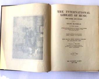 Könnte beinhalten: Der Einband des Buches "The International Library of Music" mit dem Titel in Fettdruck und den Worten "For Home and Studio" in kleinerer Schrift. Das Buch ist für Studienmaterial in vier Büchern, mit Originalstücken, technischen Übungen und erklärendem Text von Charles Dennee. Das Buch ist der zweite Band und wurde von The University Society, New York, herausgegeben.