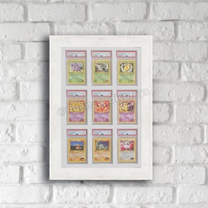 May include: A white frame with a white mount displays nine Pokemon cards in protective plastic sleeves. The cards are arranged in three rows of three. The cards are all from the first edition of the Pokemon Trading Card Game.